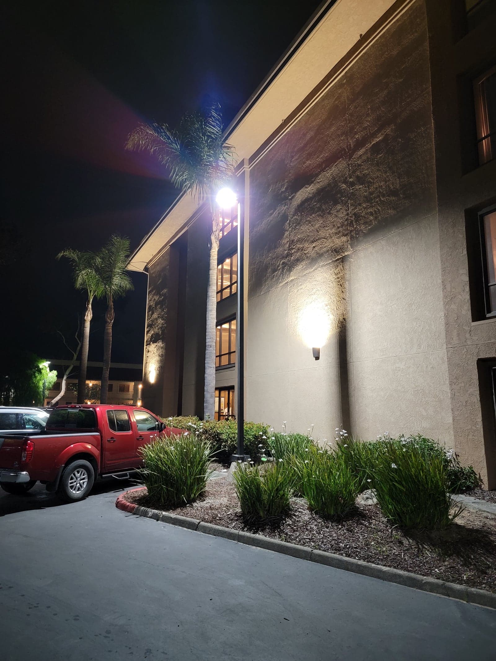 LED wall-pack fixture mounted on an exterior soffit over a guest-entry walkway
