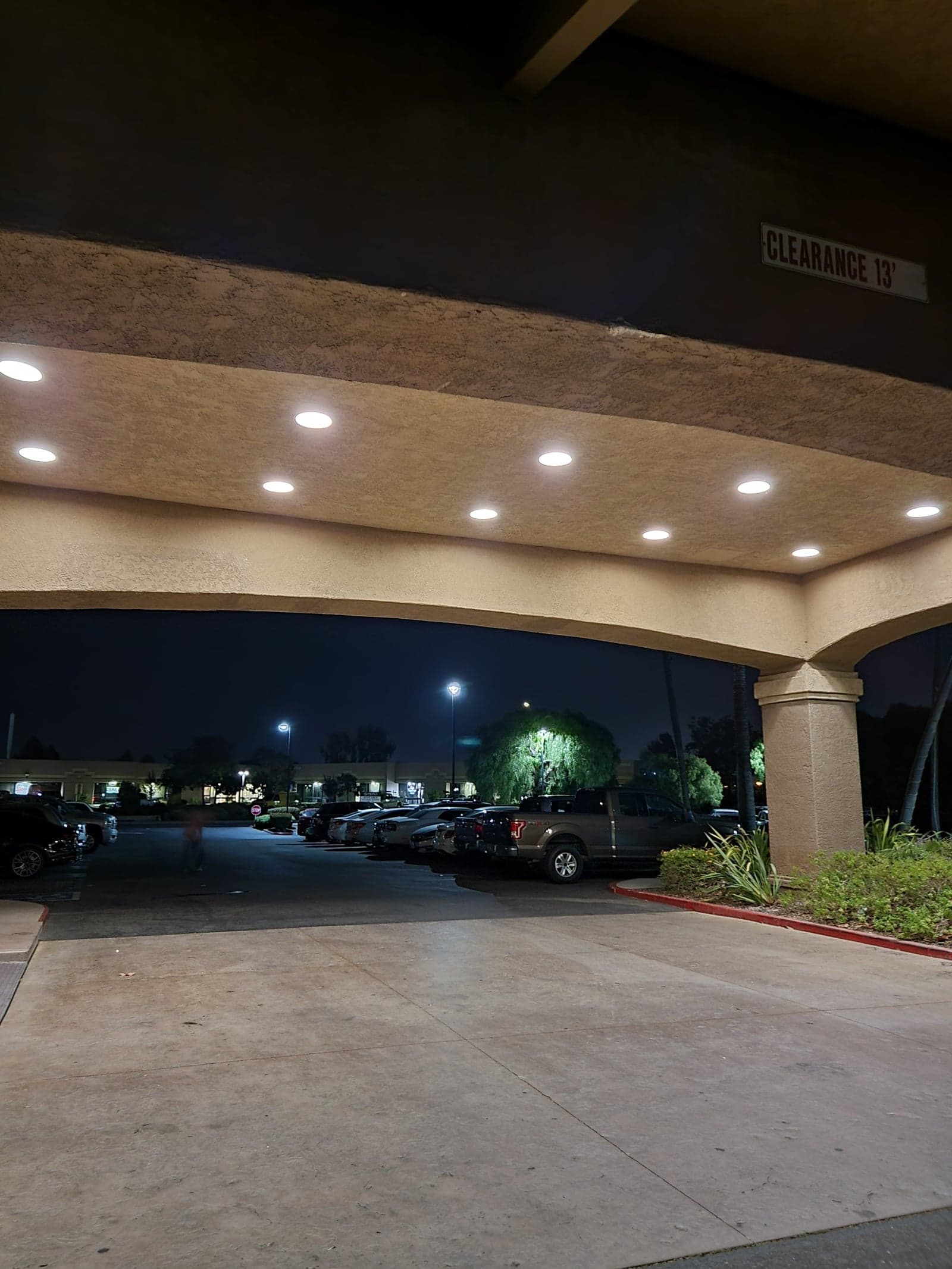 DLC-listed LED downlights in a hotel covered-entry ceiling at night, replacing legacy HID cans