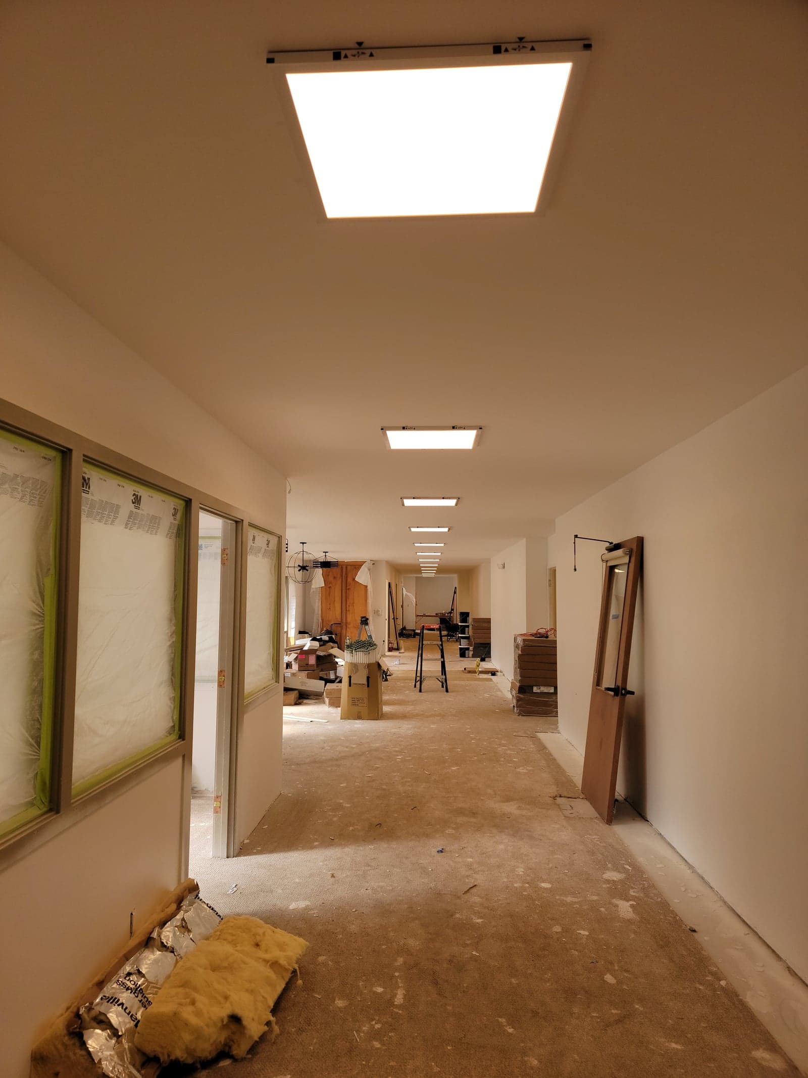 School classroom ceiling mid-install with DLC-listed 2x2 LED troffer panels replacing T8 fluorescent fixtures