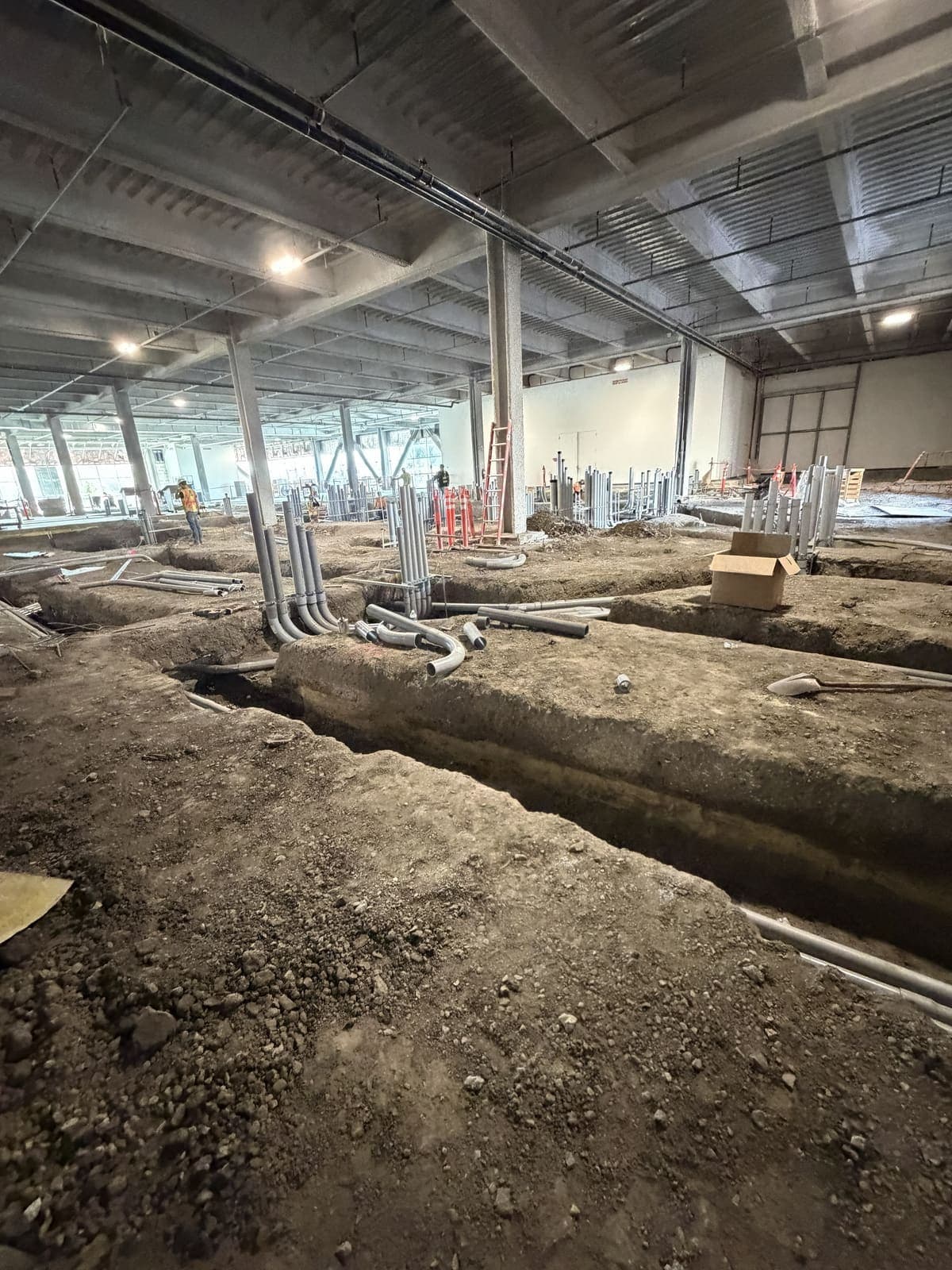 Underground feeder rough-in on a large Cupertino commercial buildout — slab-cut trenches, EMT stubs ready for cap-and-pour, all NEC-compliant routing.