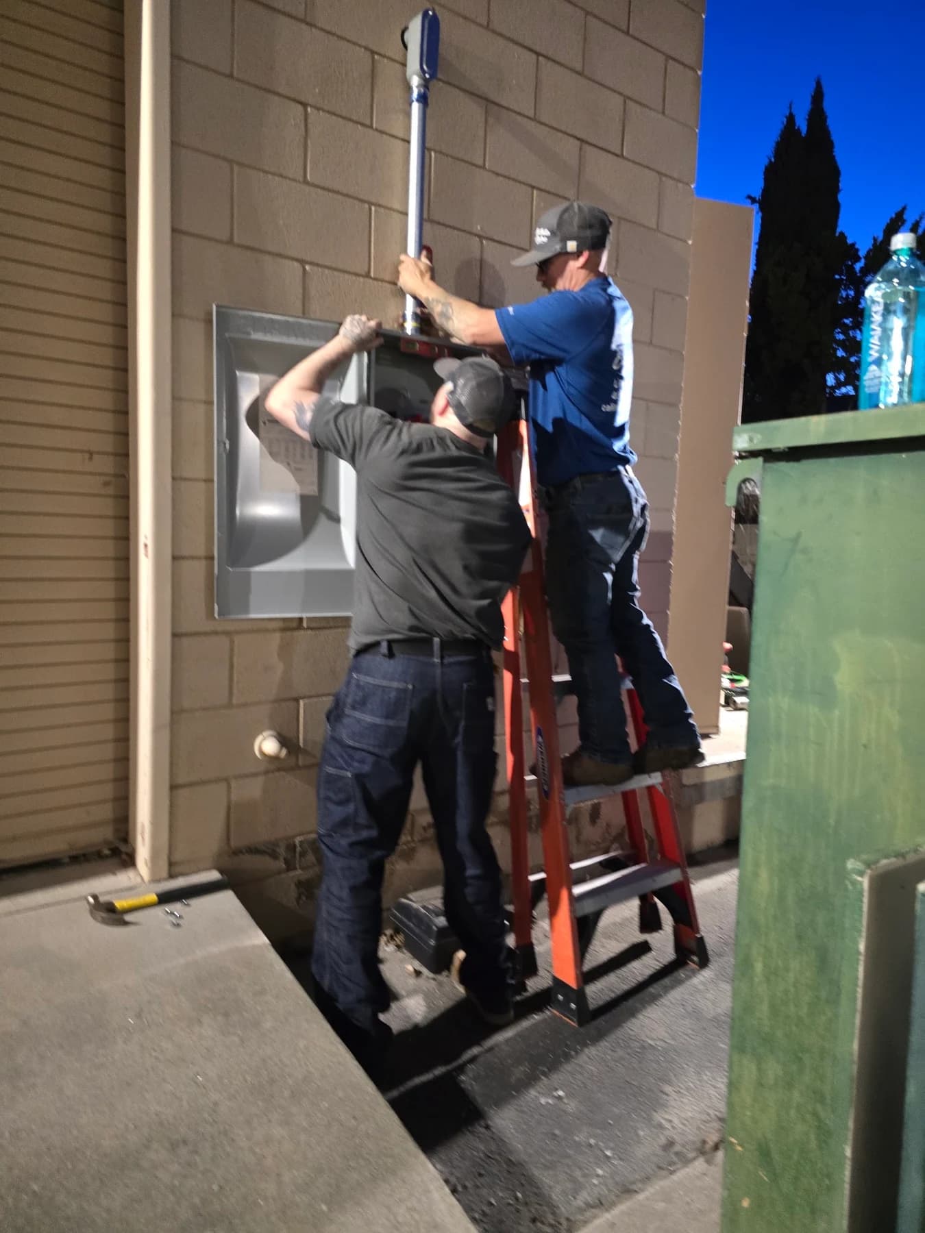 Two CRE crew members working together on an exterior electrical installation
