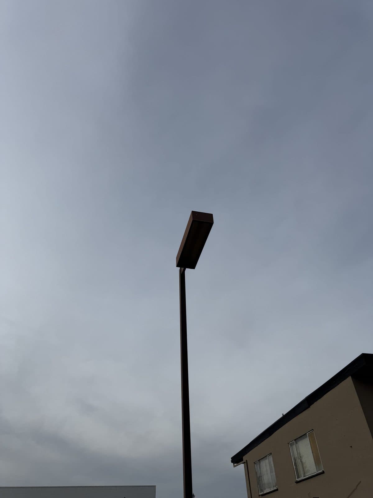 Parking-lot pole fixture dark and out of service during a daytime site survey