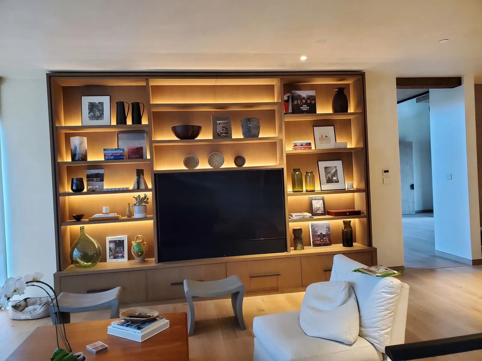 Warm integrated lighting inside a floor-to-ceiling built-in cabinet wall