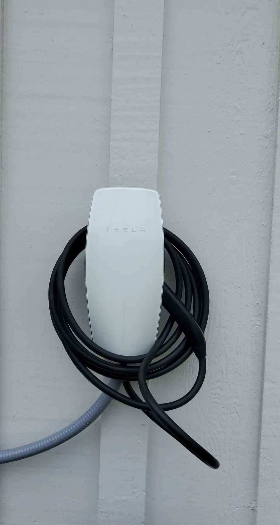 Tesla wall connector with coiled cable mounted on a residential wall