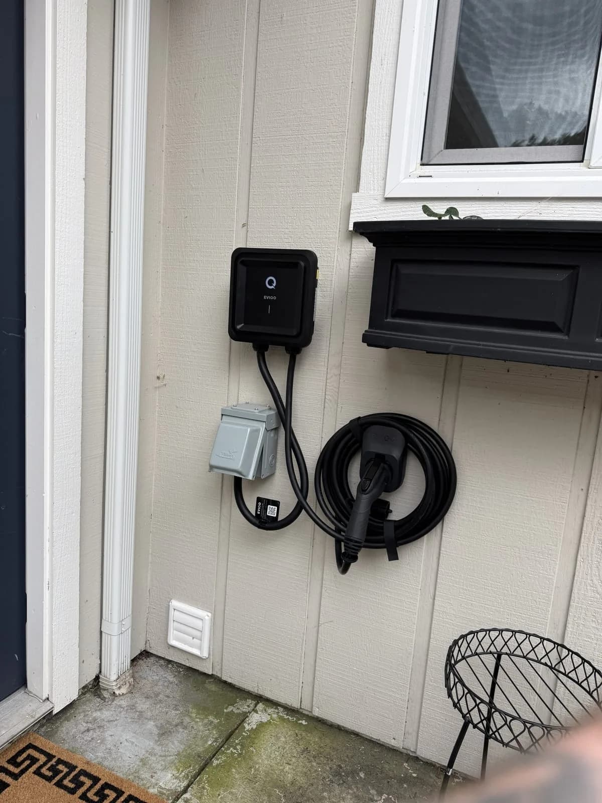 Wall-mounted EV charger and cable beside a residential entry