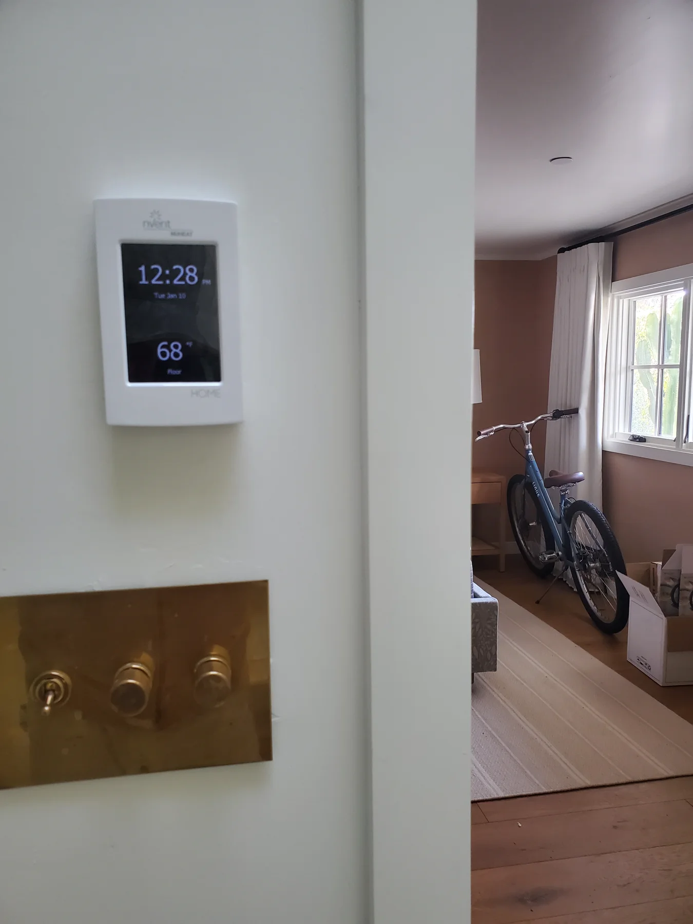 NUHEAT floor-heating thermostat above a brass wall-control plate