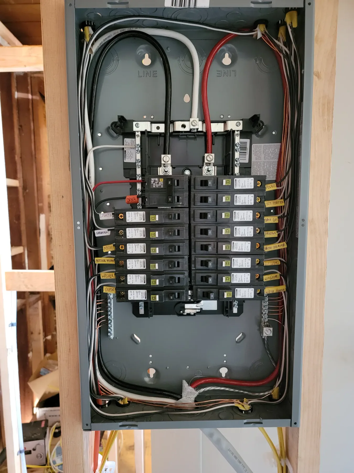 Residential load center open in framing with breakers and labelled circuits visible