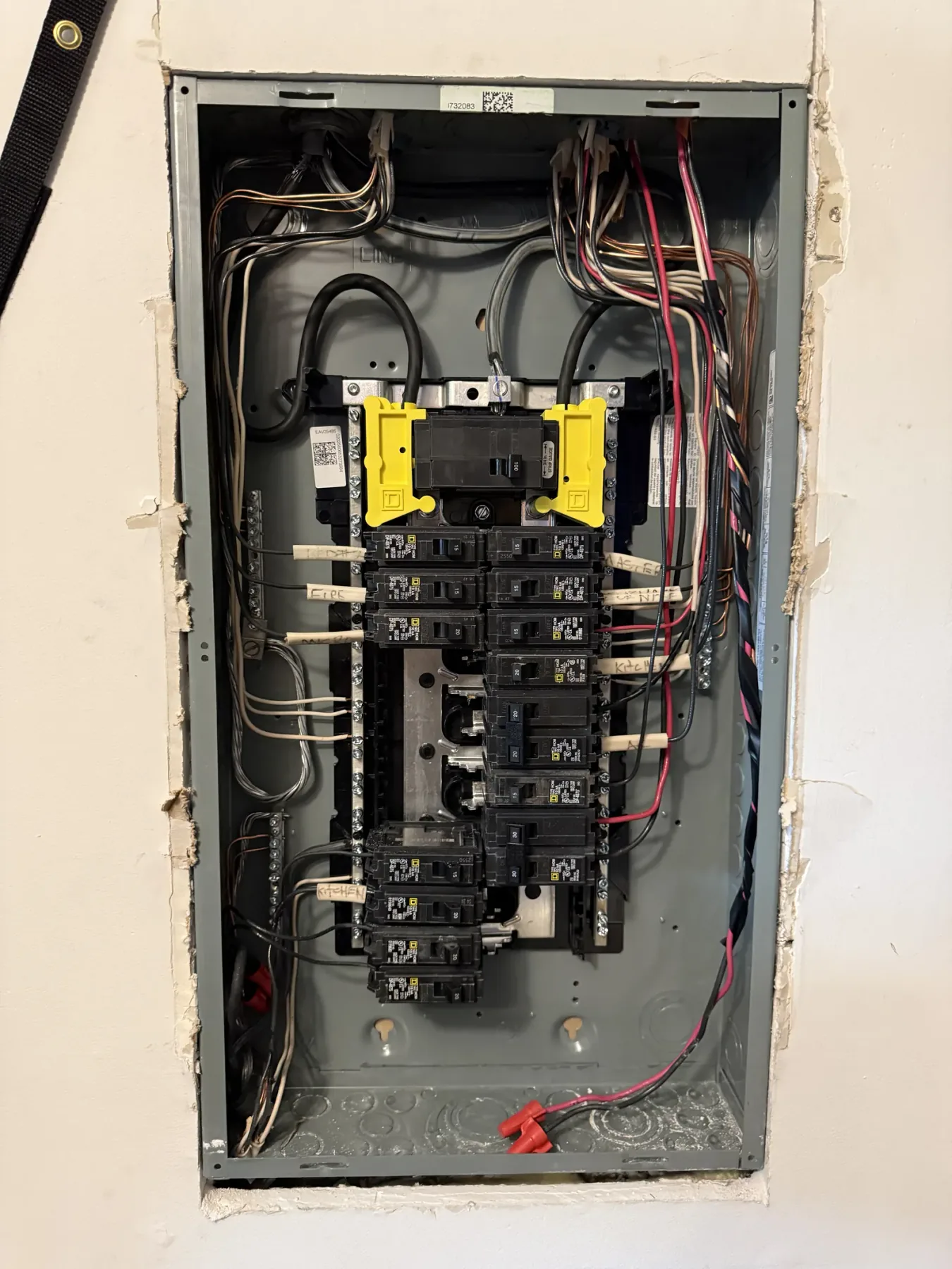 Residential subpanel open in framing with breakers and feeders visible