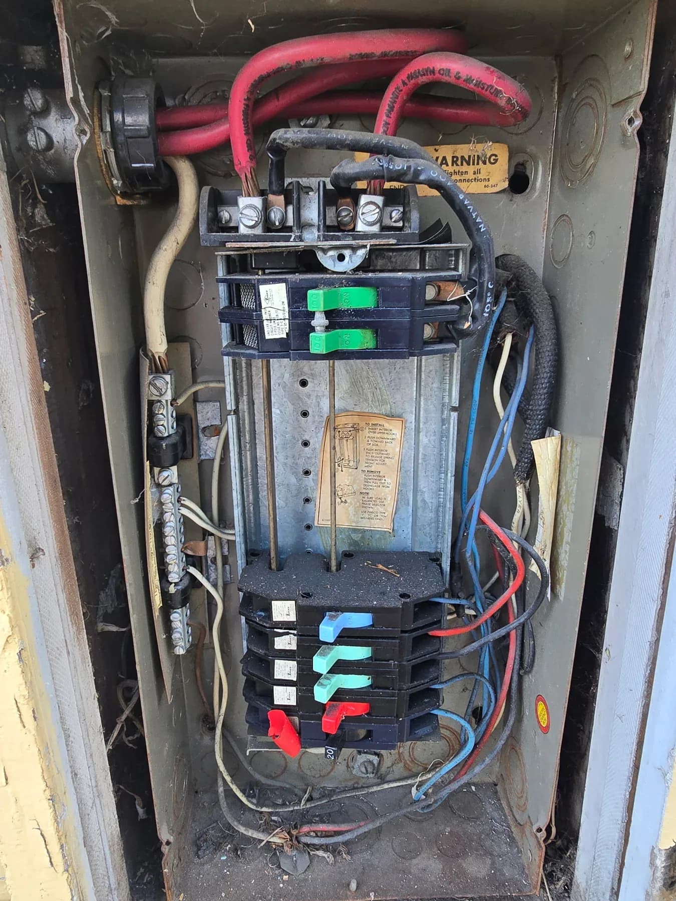 Existing panel interior with colored breakers beside a utility meter