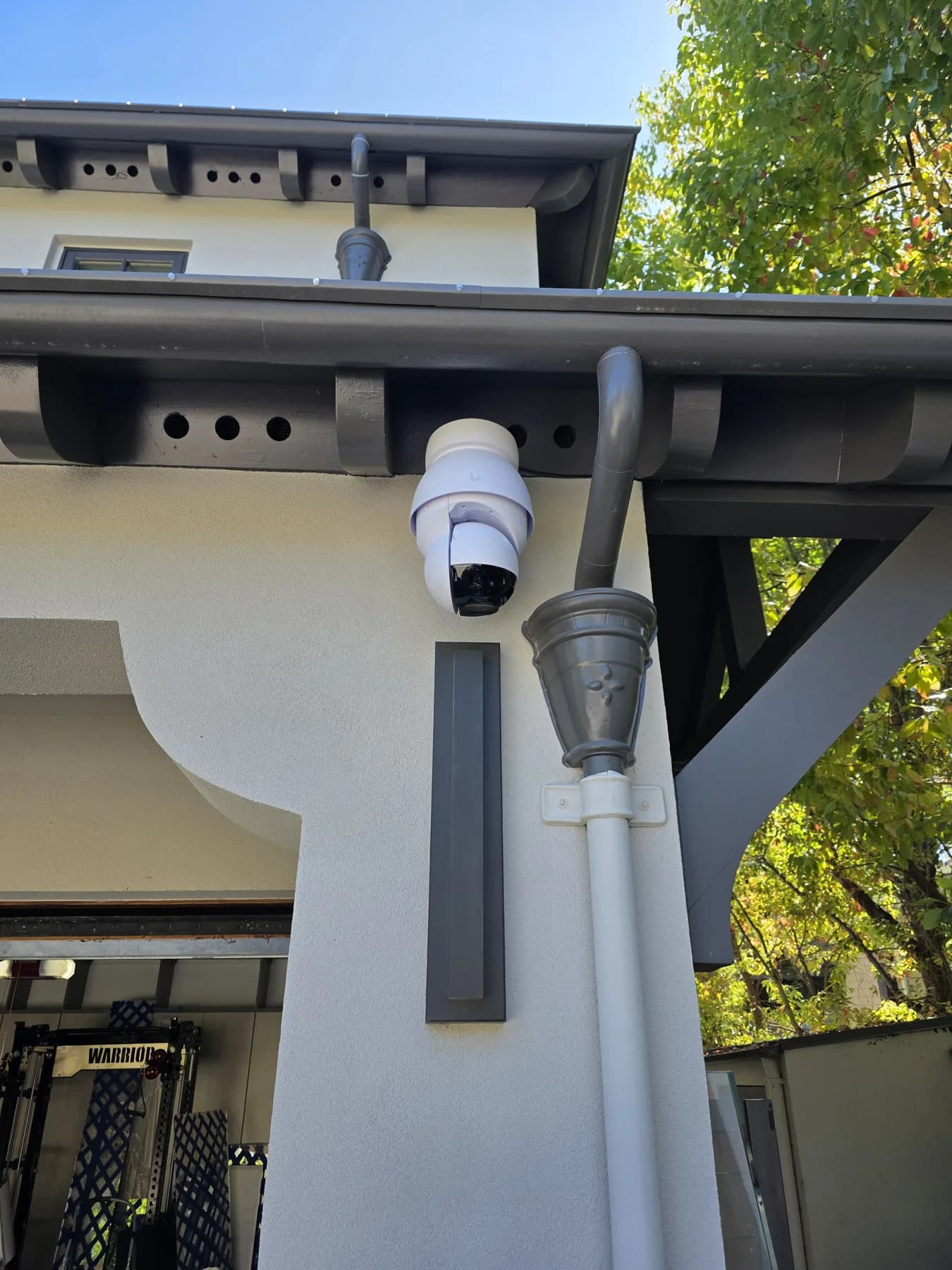 White dome security camera mounted beneath a garage eave