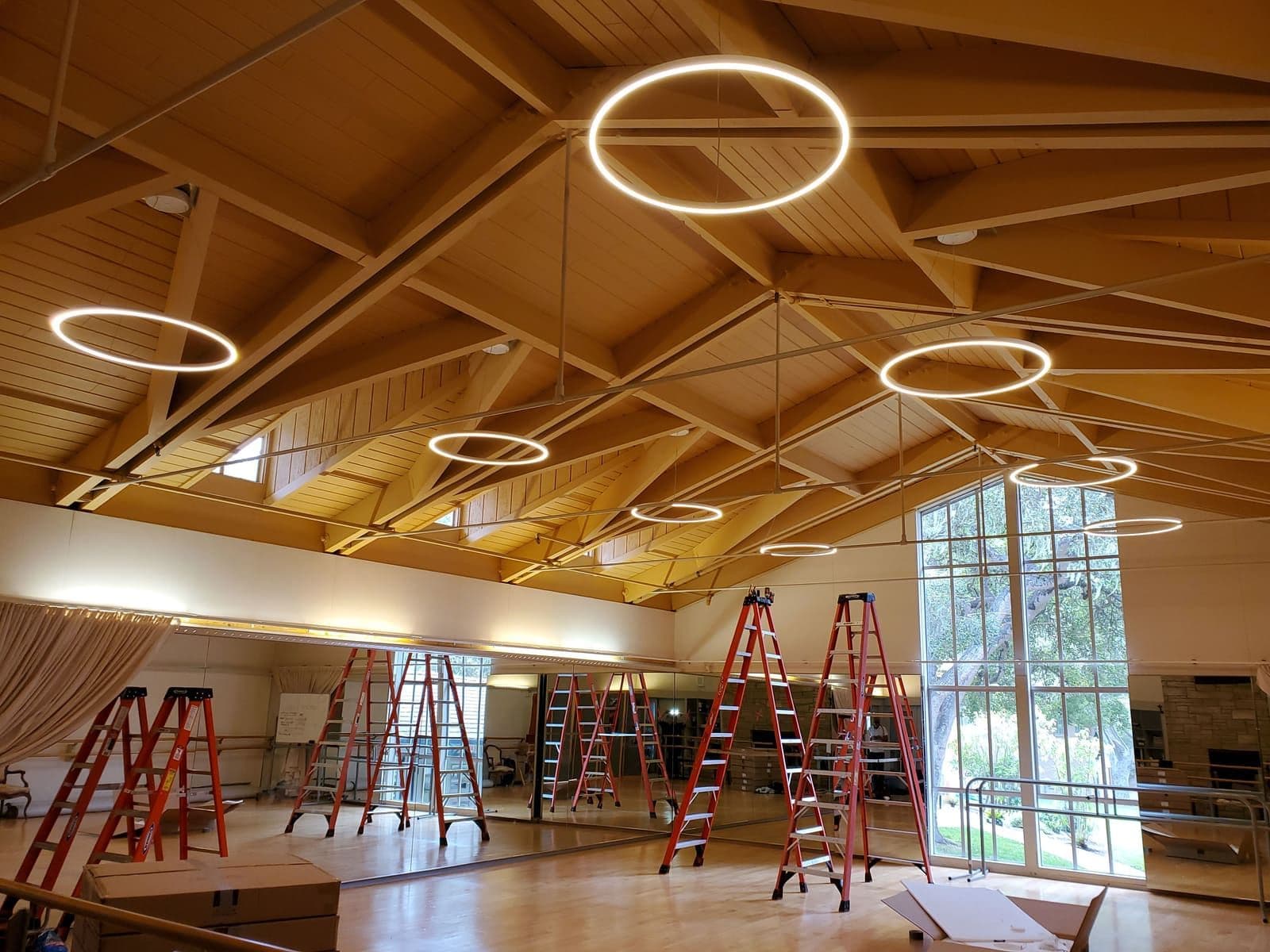 Illuminated ring fixtures beneath a wood ceiling during a Monterey lighting installation